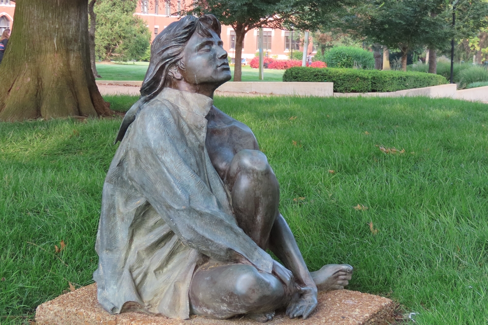 A close-up of a statue of a contemplative young woman on SLU's campus.