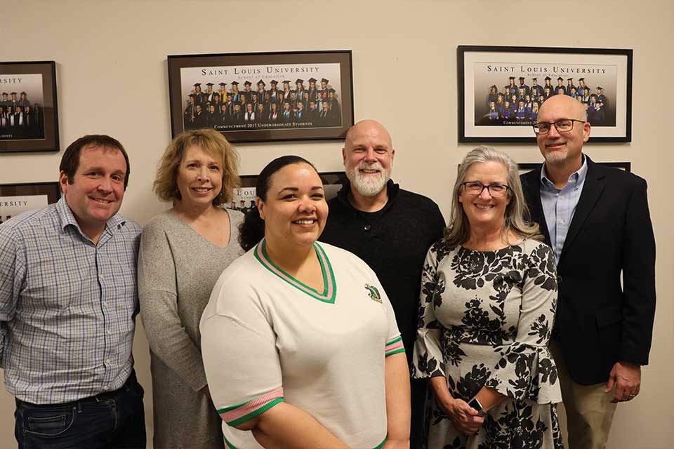 A group of SLU professors stand within the Dean's office in the School of Education after announcing a major grant for the school to improve teaching ranks within underserved communities. 
