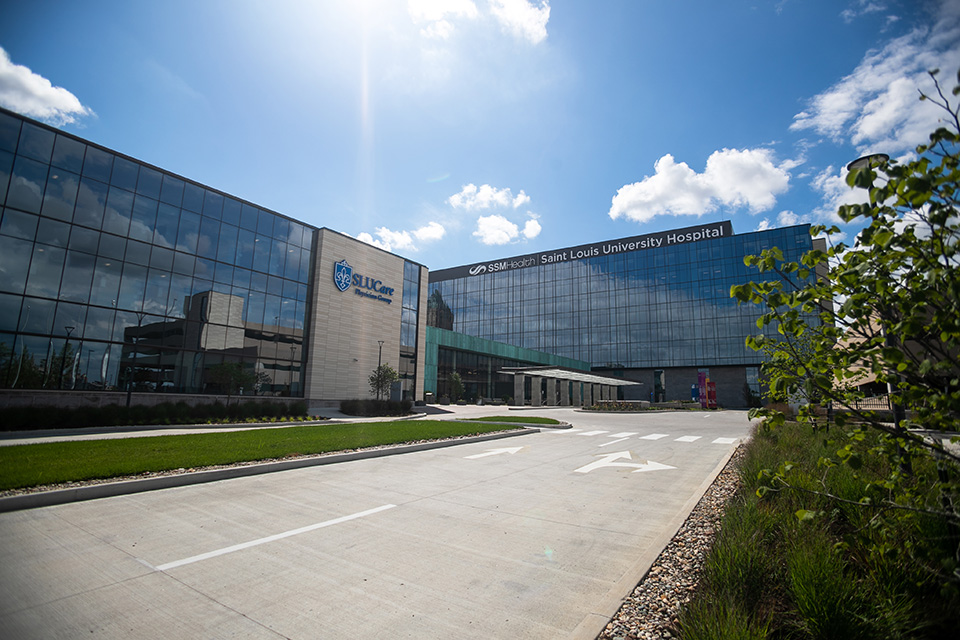 A photo of the outside entrance of the Saint Louis University Hospital Building with the sun shining