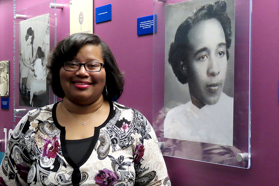 Devita Stallings, Ph.D., RN, associate professor of nursing in the Trudy Busch Valentine School of Nursing stands before the school's heritage wall in front of a photo of its first African-American graduate.