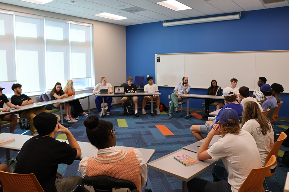 A professor engages students in a roundtable discussion. 