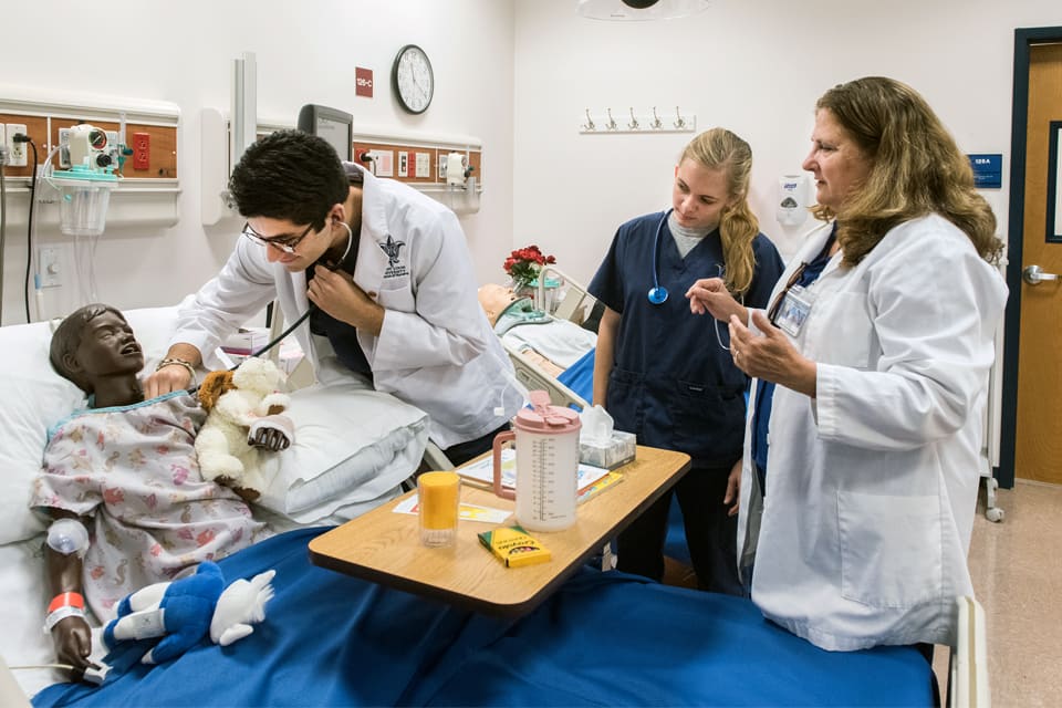 SLU nursing student and professors work together in lab with patients