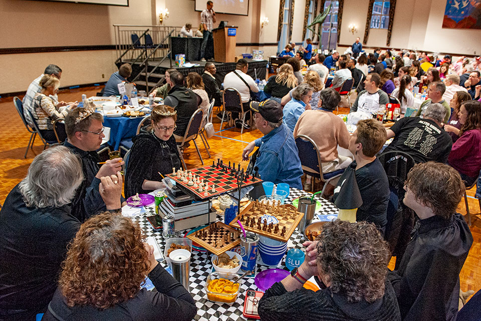 Crowded room of trivia participates with their tables decorated with a board game theme