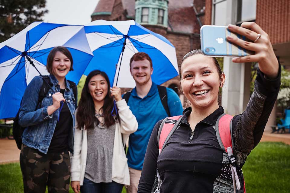 Students taking a selfie under a blue SLU umbrella