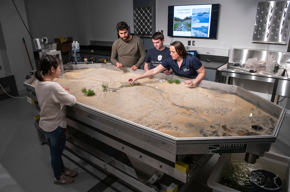 Amanda Cox and Sofie Liang demonstrate open channel flow simulations using the stream table in the WATER Institute Hydraulics Lab to two students
