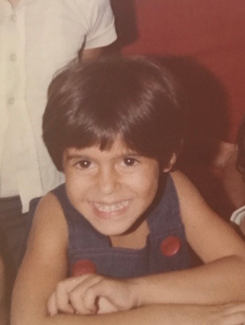 Alameh as a child, posing with a smile.