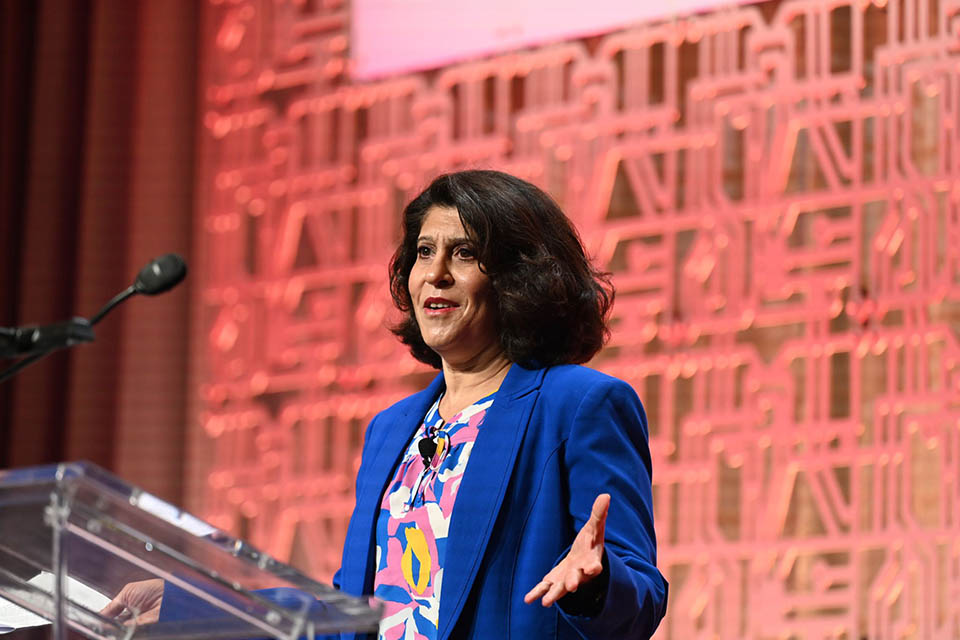 Alameh speaks at a podium during a conference.
