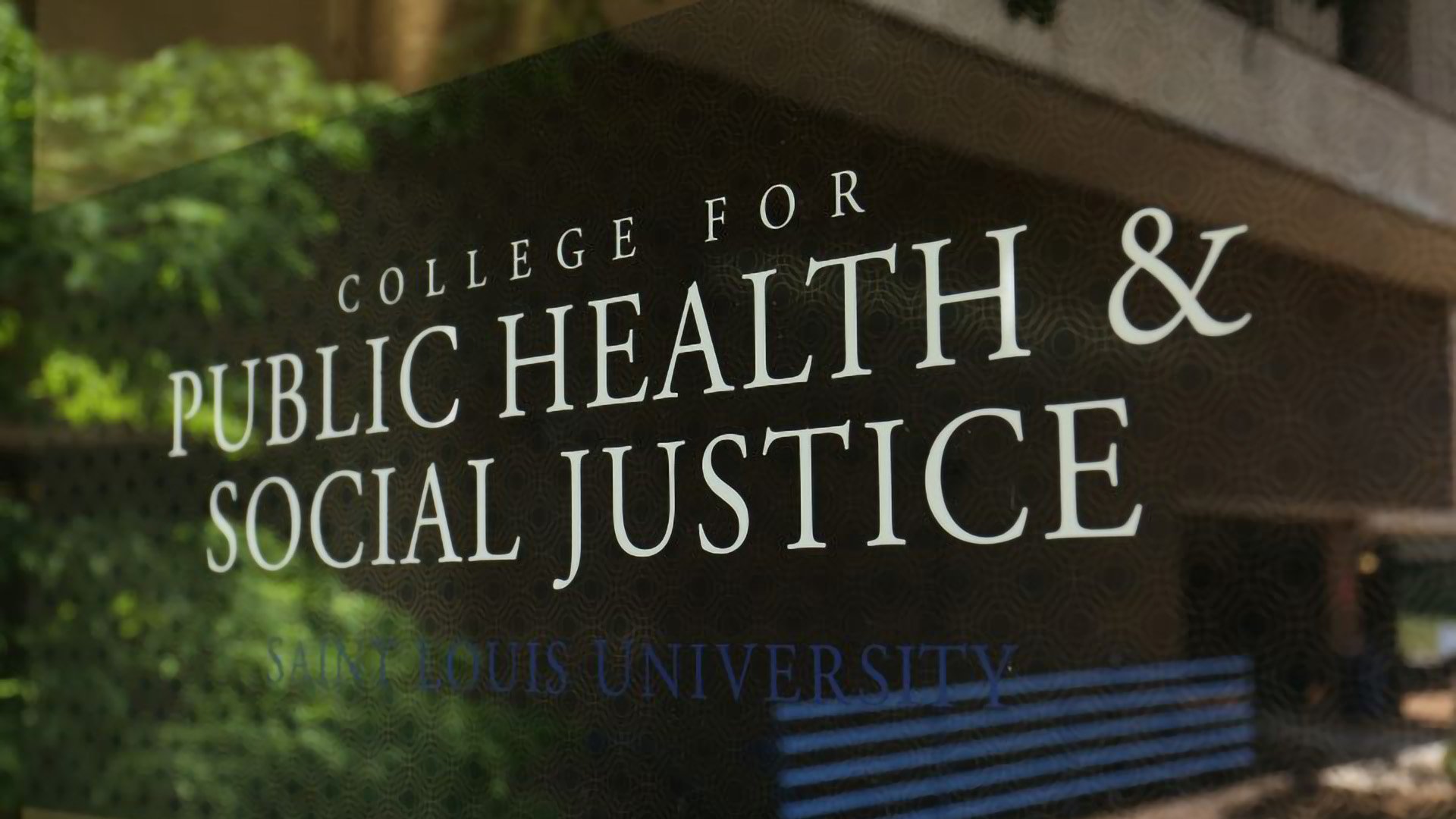 A door at the Salus Center on SLU's campus with the words "College for Public Health and Social Justice Saint Louis University" on it.