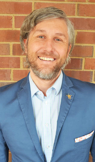 Interim Dean, Scott Duellman, standing in front of a brick wall