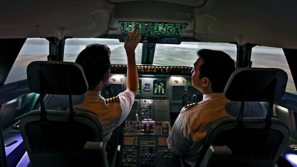 Two students push buttons in a flight stimulator.