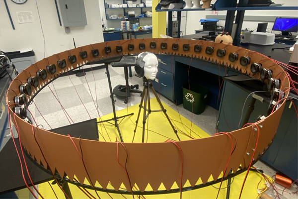 Hearing Aid Research in Yan Gai's Lab A mannequin head wearing headphones sits in the middle of a large circle containing small machines.