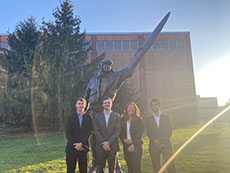 Team members posted outside in front of a pilot statue