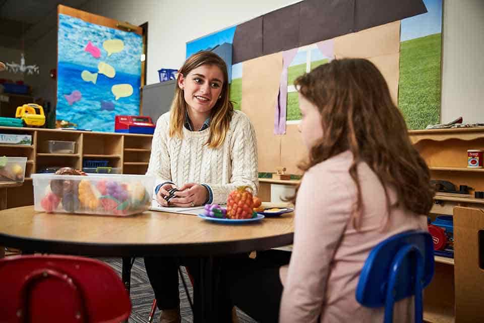 A SLU student speaks with a young client in a classroom.