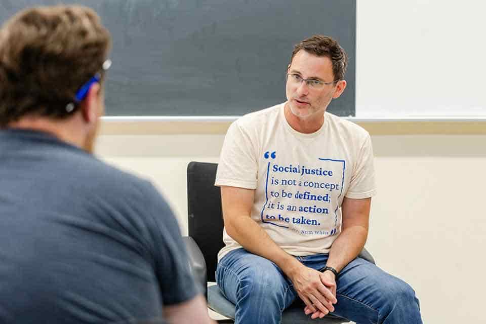 A man speaks to a room of students.