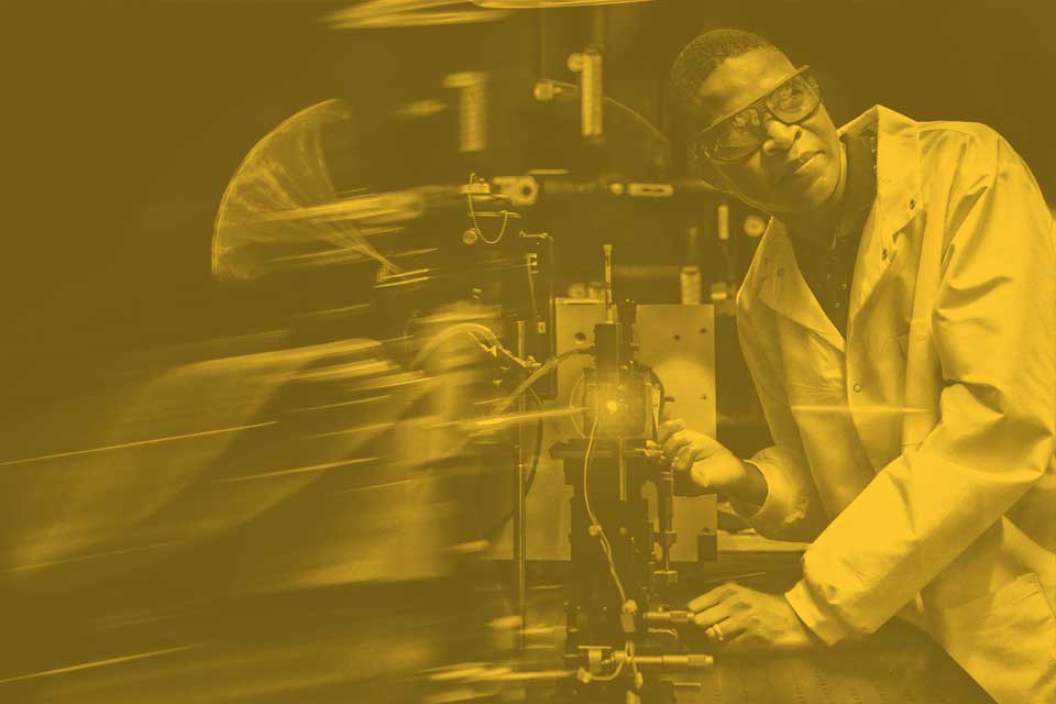 A researcher examines a laser in a SLU faculty lab