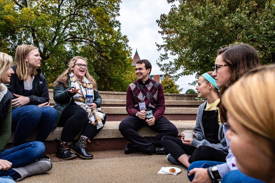 Jesut priest having a conversation on the SLU Clocktower steps