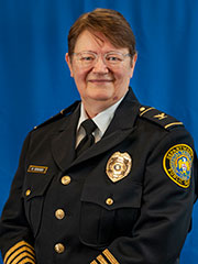 Short haired woman wearing a SLU Public Safety captain uniform, photographed against a solid background