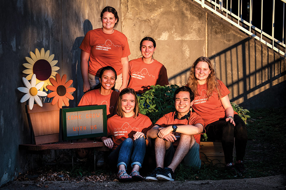 Six students from Road to a Greener SLU service group gather near the garden on campus.