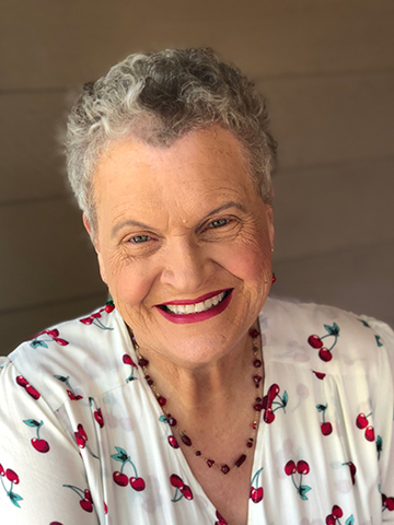 Marianne Muellerleile wearing red lipstick and a blouse with cherries on it