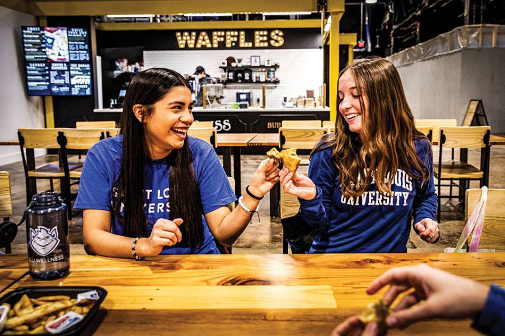 Two female SLU students enjoy treats at the City Foundry STL food hall
