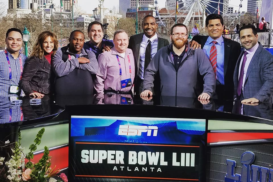 Beasley stands with colleagues behind an outdoor sign for Super Bowl LIII