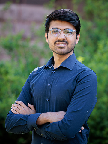 A profile photo of a male graduate student from India, wearing glasses and a dark blue collared shirt