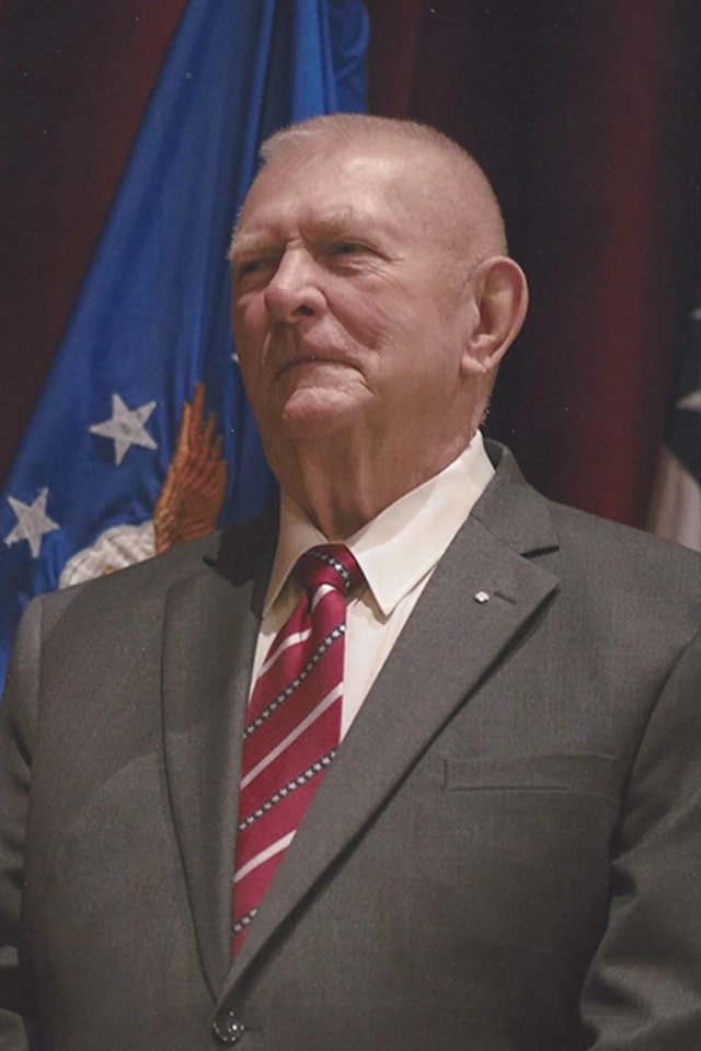 Portrait of Gene Kranz standing in front of a flag