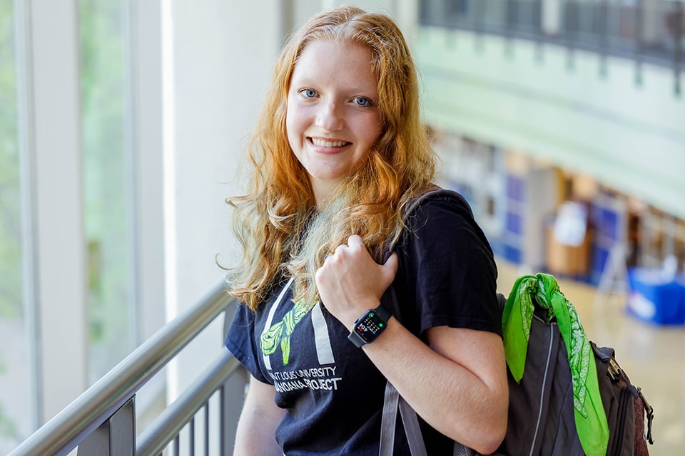 SLU student Allison Twohig poses with a backpack and green bandana