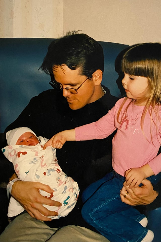 Sowell holds his newborn daughter while the eldest daughter sits on his lap