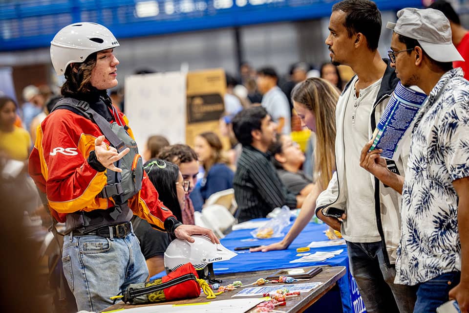 A student in paintball gear chats with students during the SLU Involvement Fair.