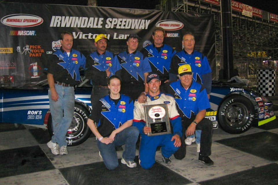 Sullivan poses with her pit crew team in front of a race car