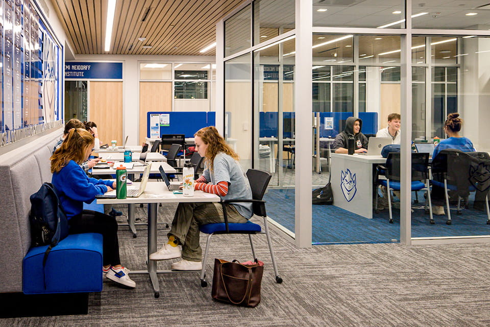 Students sit and talk at tables and chairs.
